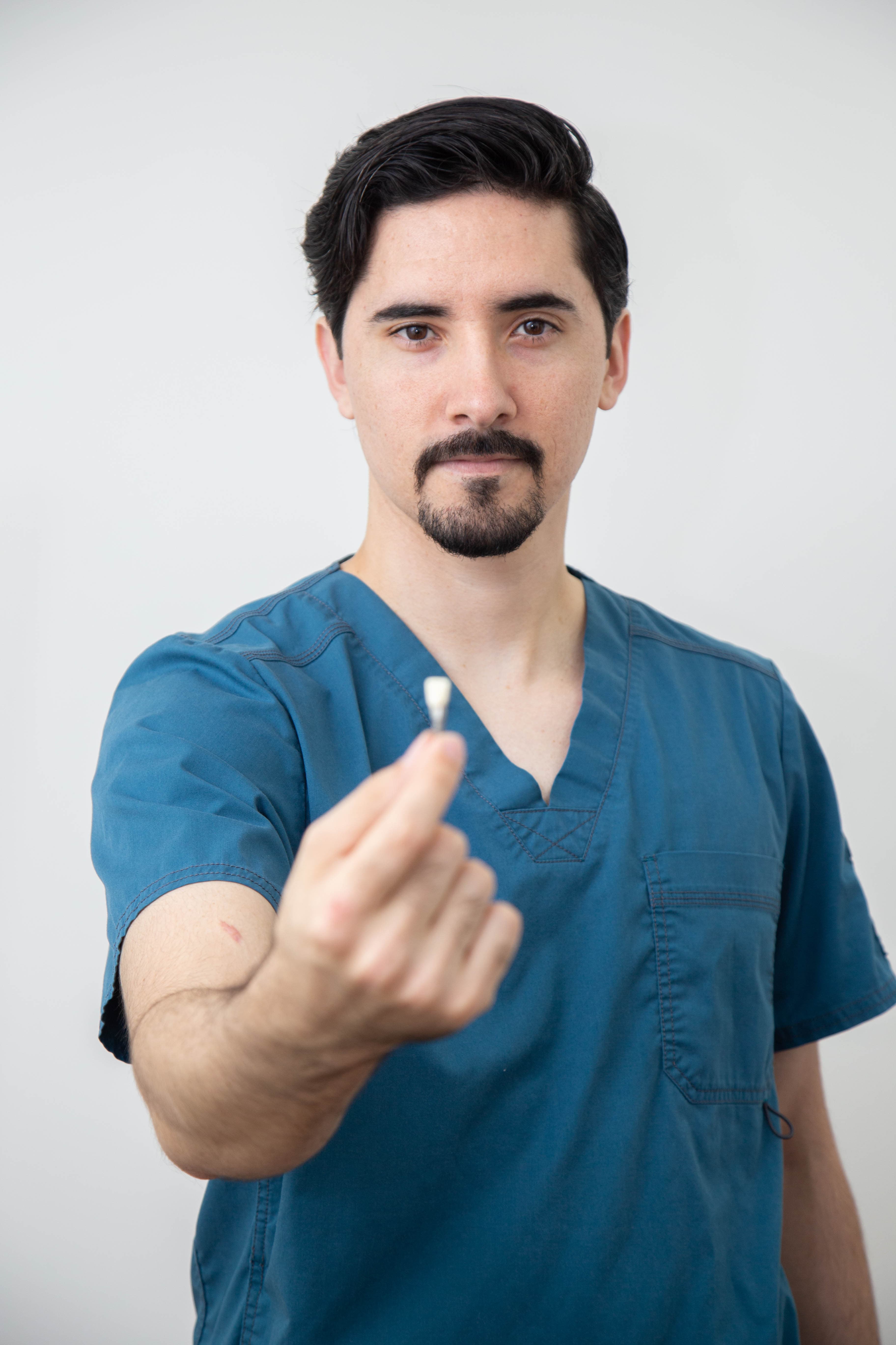 Dr. Joel mostrando un implante dental de titanio
