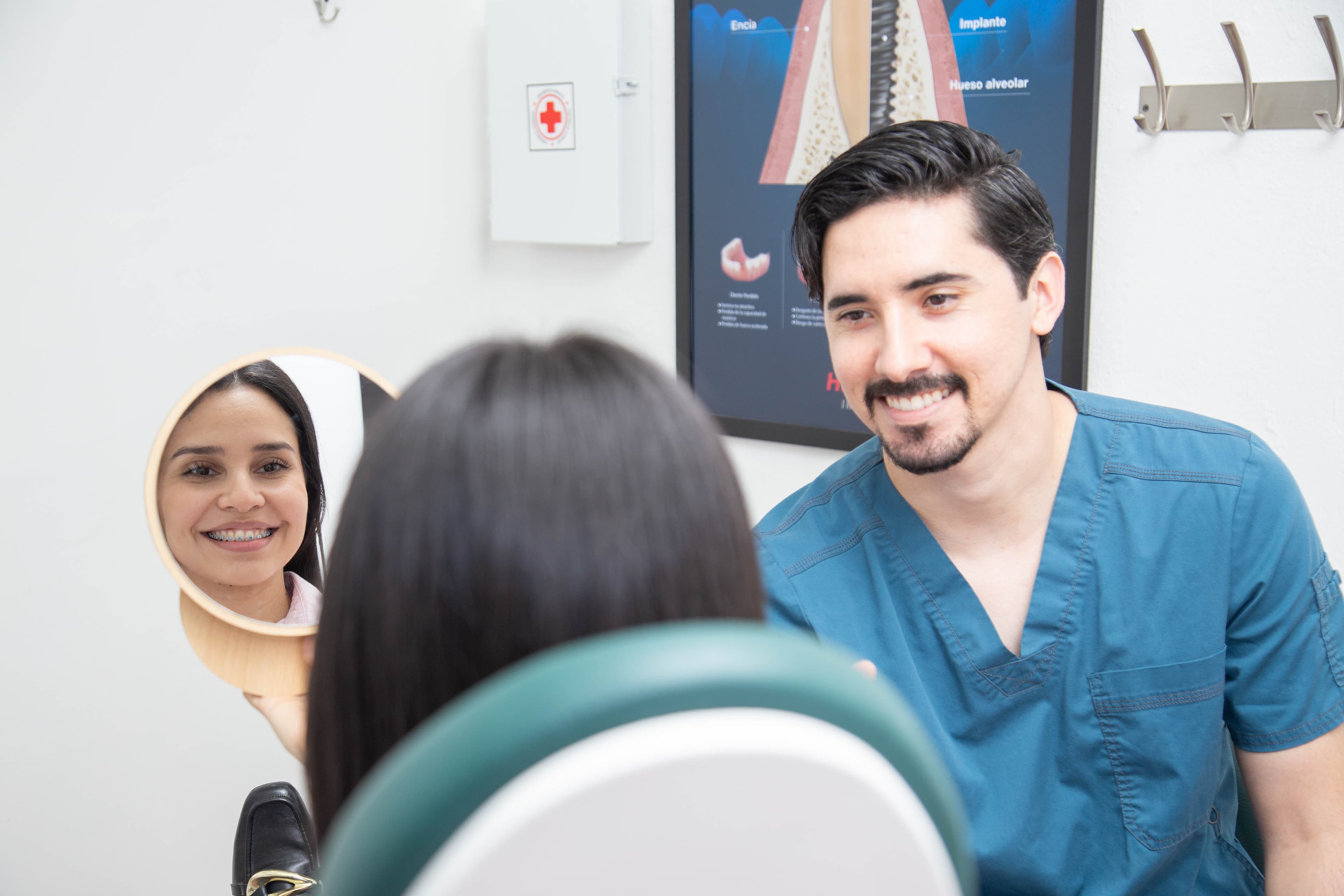 Paciente sonriendo frente al espejo junto al Dr. Joel